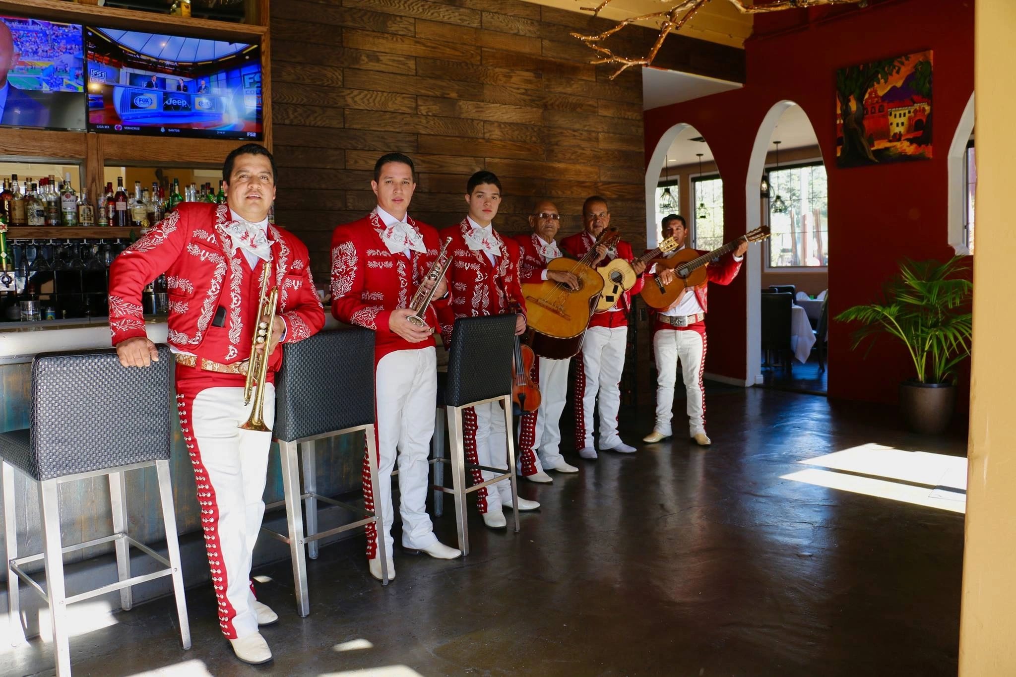 Mariachi Real De Oxnard performing in red suits at a restaurant